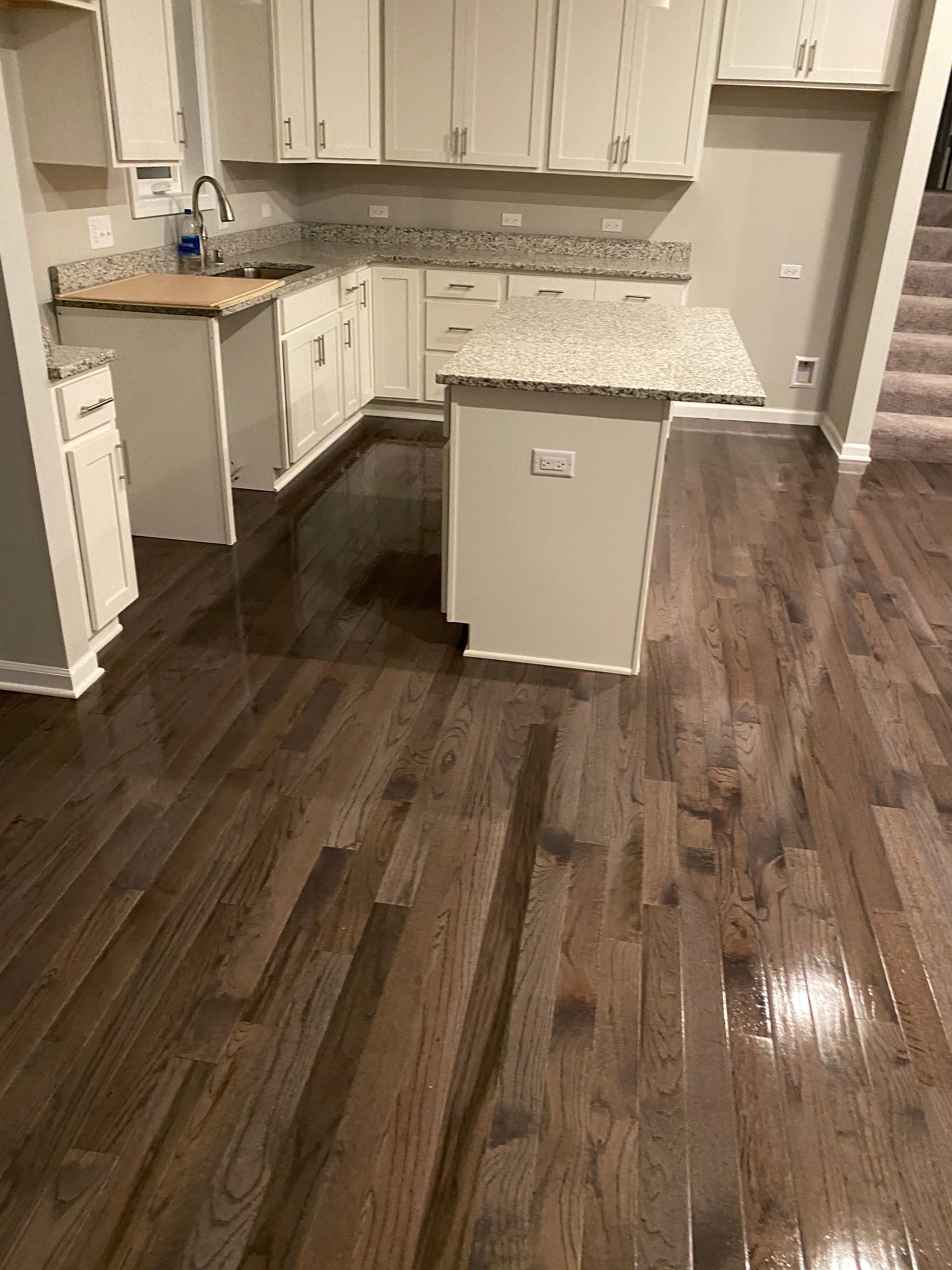 Kitchen with dark hardwood floors, white cabinets, granite countertops, and an island.