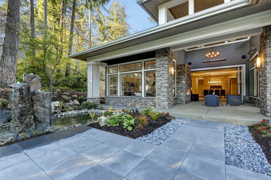 A large house with a patio and a pond in front of it.