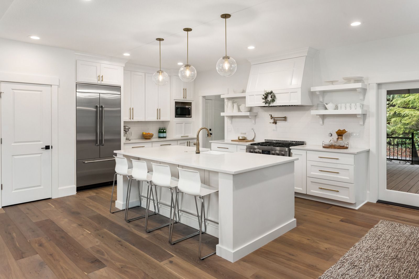 A kitchen with white cabinets , stainless steel appliances , hardwood floors and a large island.