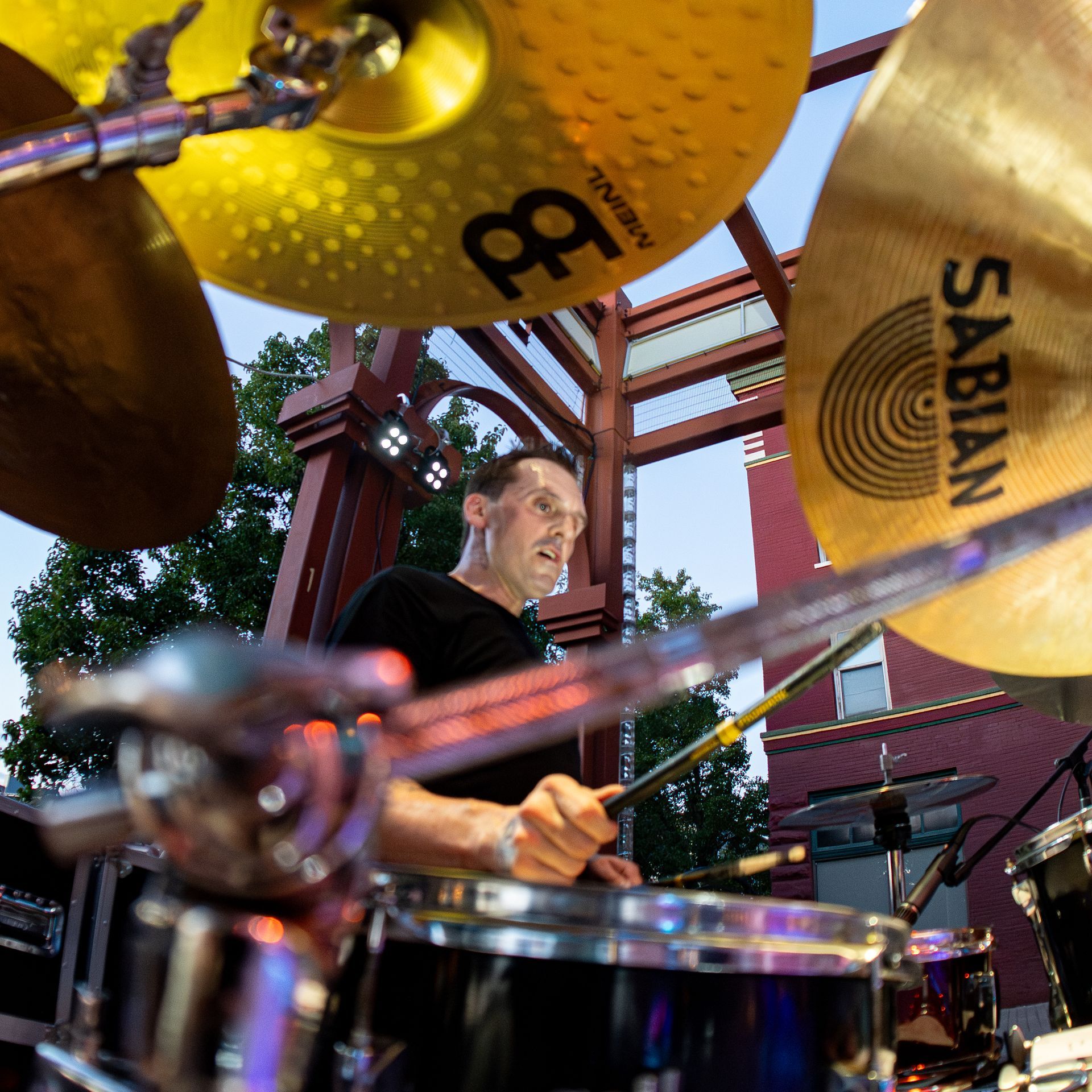 A man singing into a microphone while playing drums