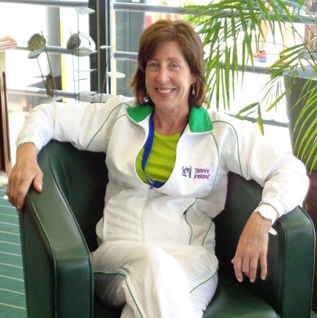 Smiling woman in white jacket seated in a green chair in a bright office lounge