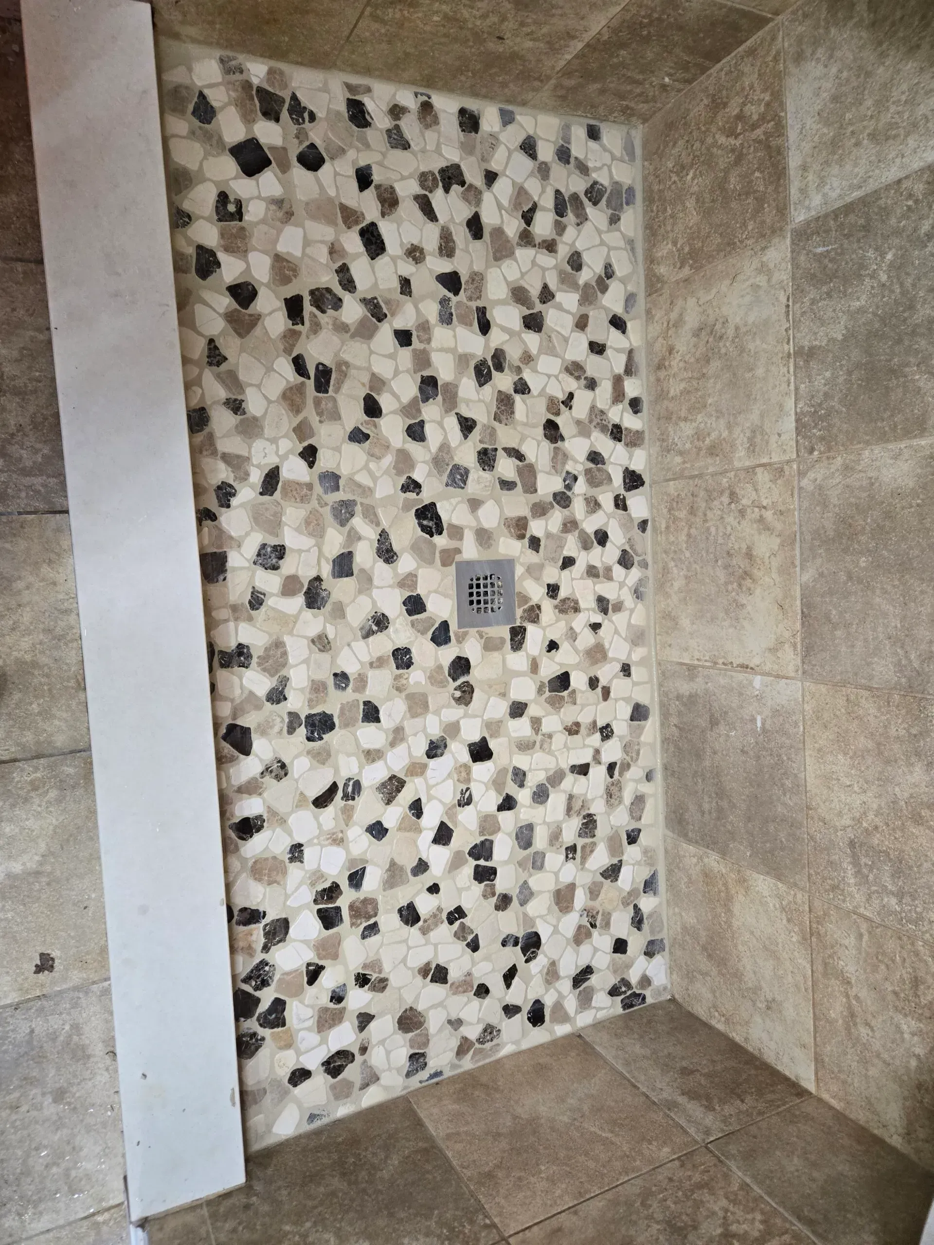 A walk in shower with a tiled wall and floor