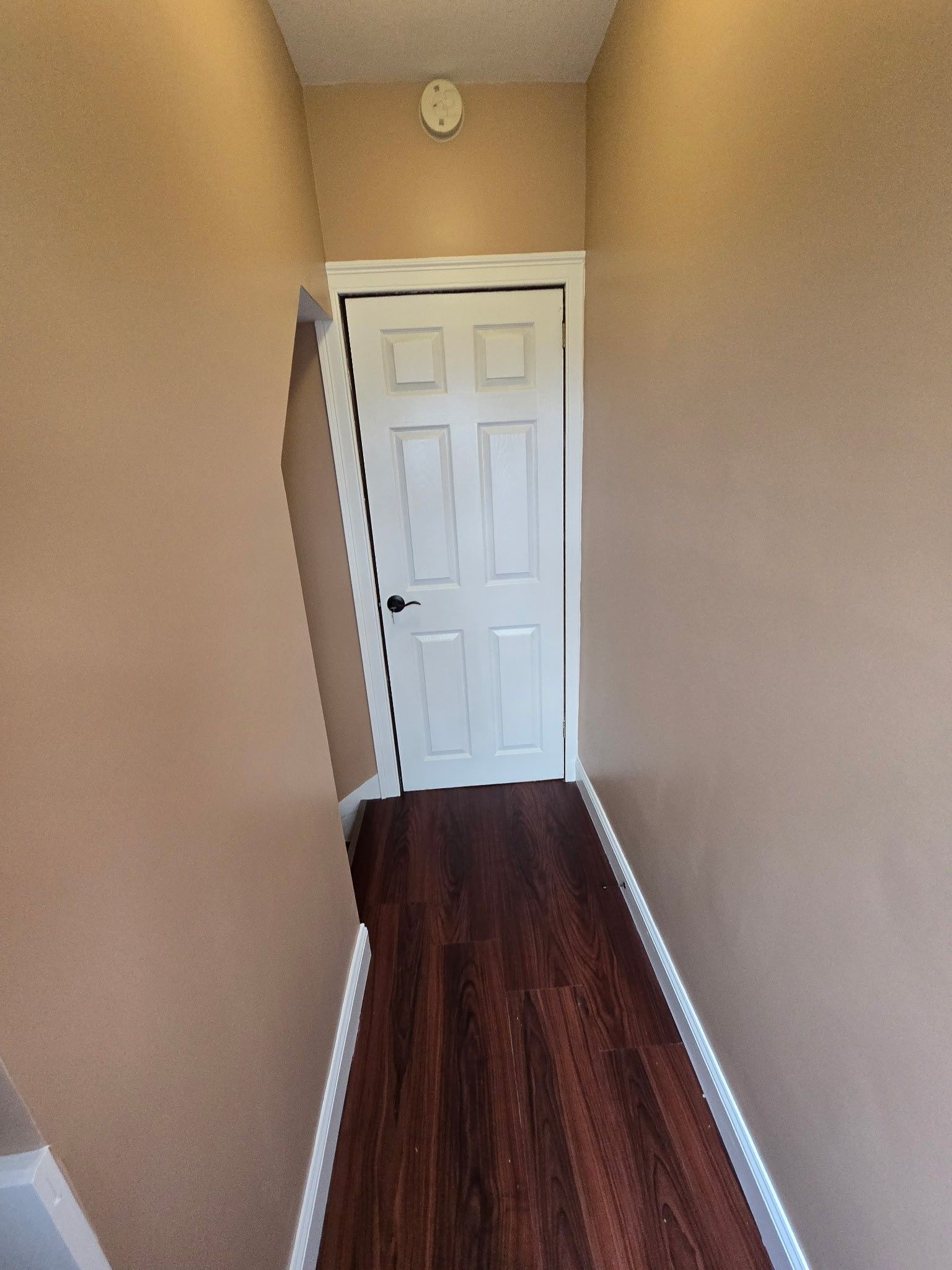 A hallway with a door and a clock on the wall.