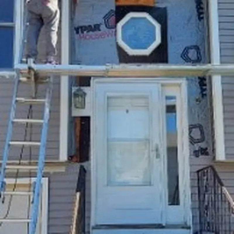 A man is standing on a ladder on top of a house.