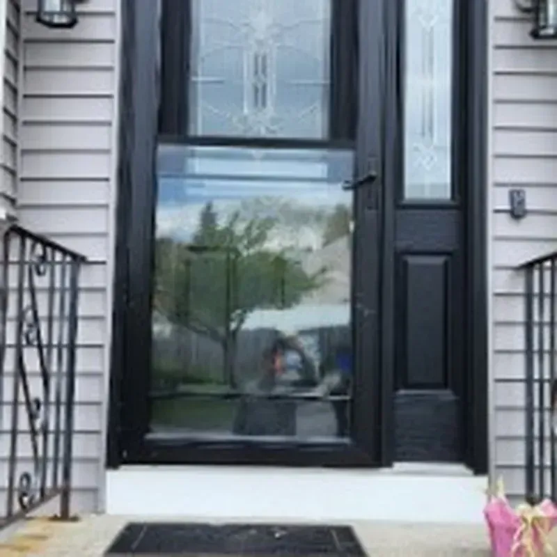 A black door with a stained glass window is on the front of a house.