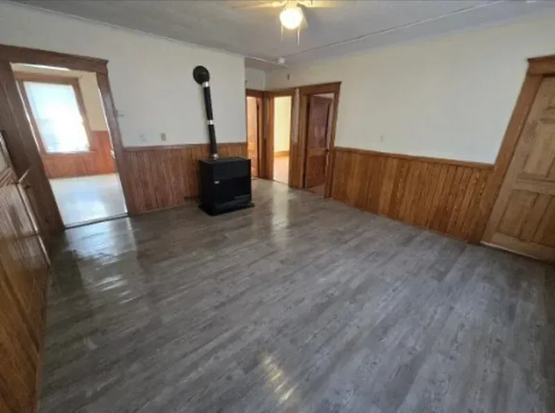 A living room with wood paneling and a wood stove