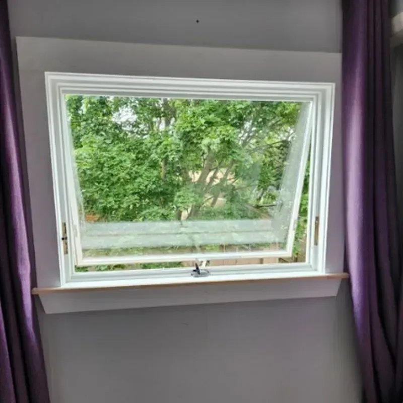 A bedroom with purple curtains and a window with a view of trees.