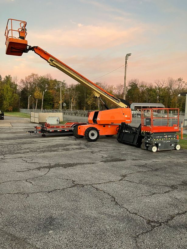 A large orange aerial lift is parked in a parking lot.