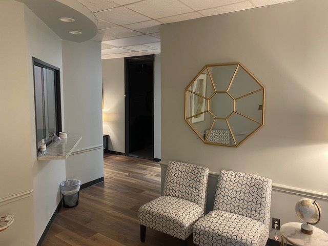 A waiting room with two chairs and a mirror on the wall.