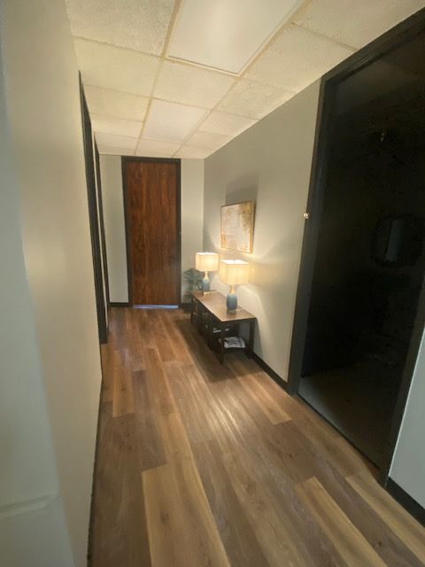 A long hallway with hardwood floors and a wooden door.