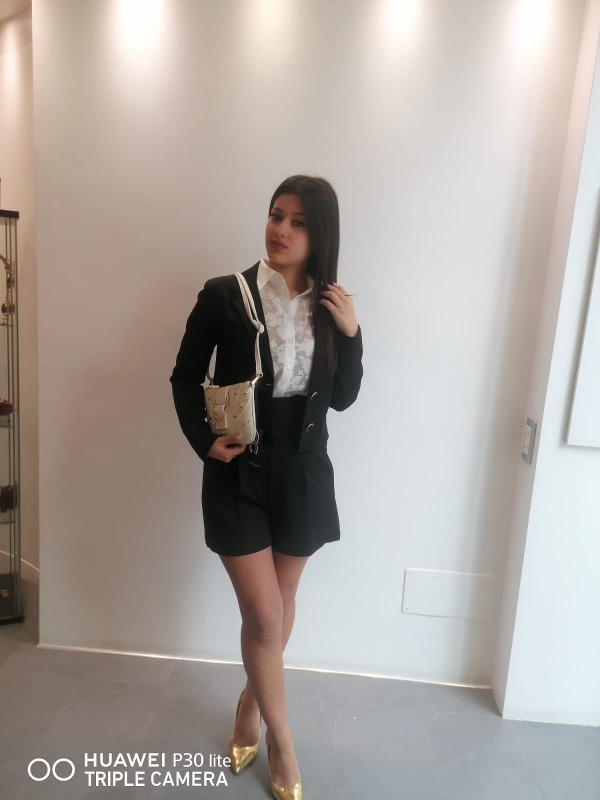 Una donna è in piedi in una stanza e indossa una giacca nera e pantaloncini corti.