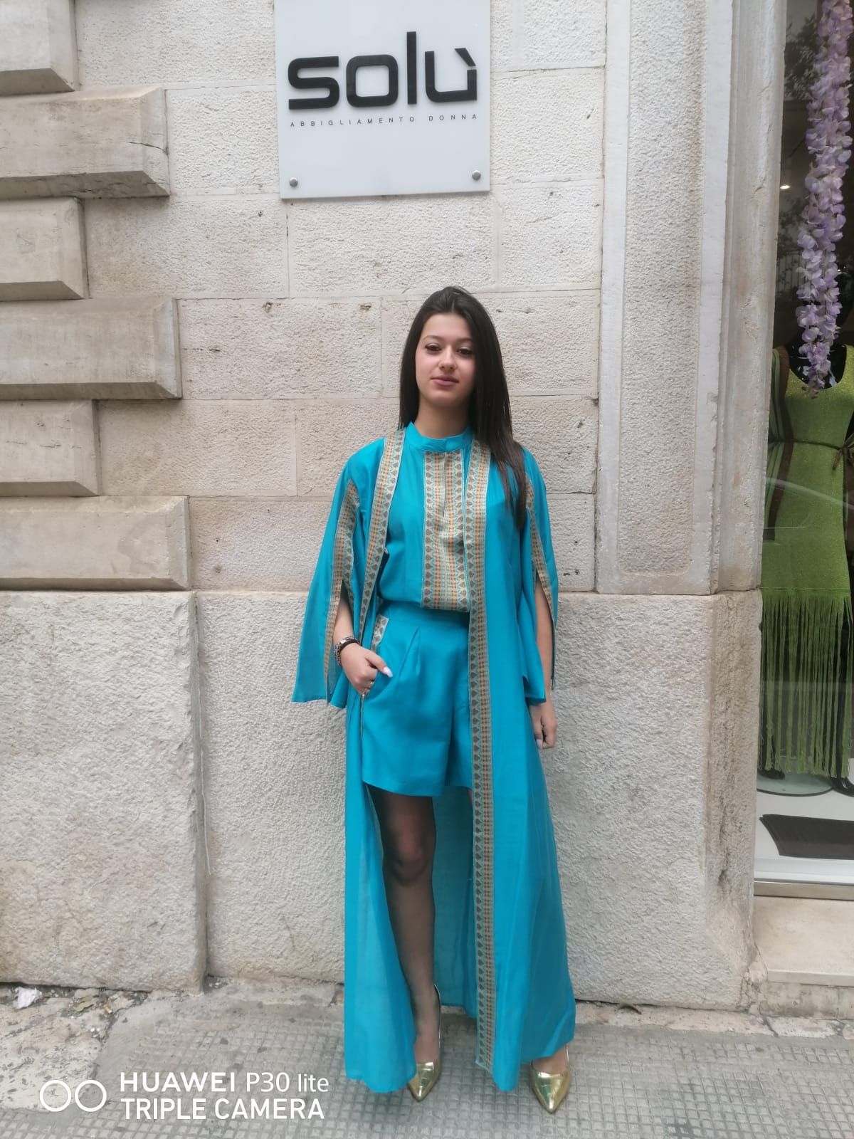 Una donna in un vestito blu è in piedi davanti a un cartello che dice solu