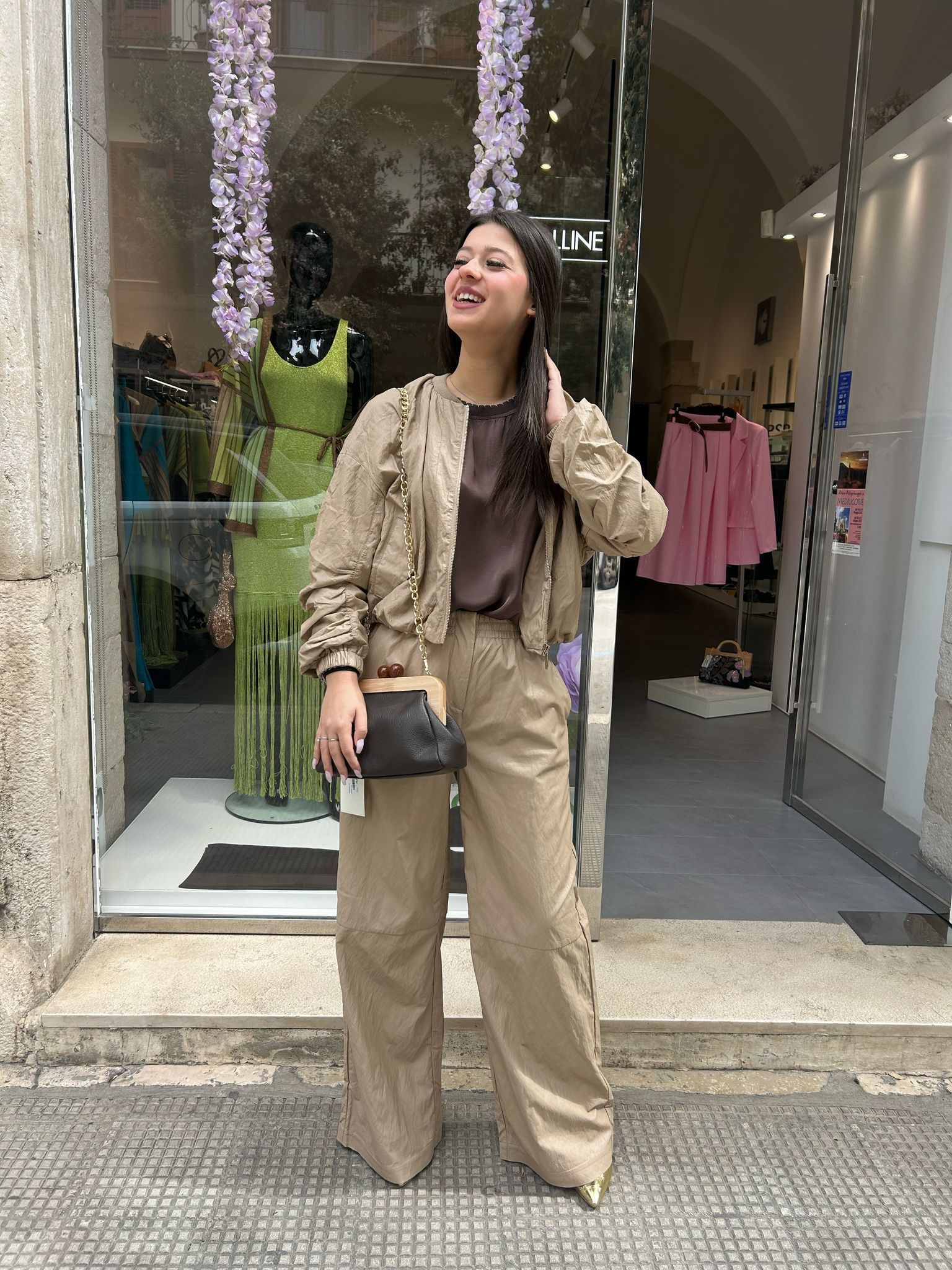 Una donna è in piedi davanti a un negozio con una borsa in mano.