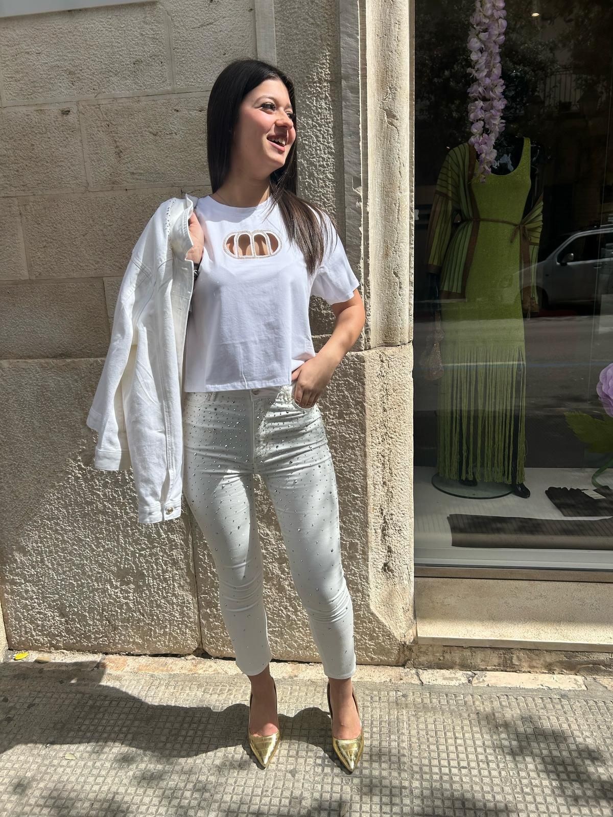 Una donna che indossa una camicia bianca e pantaloni bianchi è in piedi davanti a un negozio.