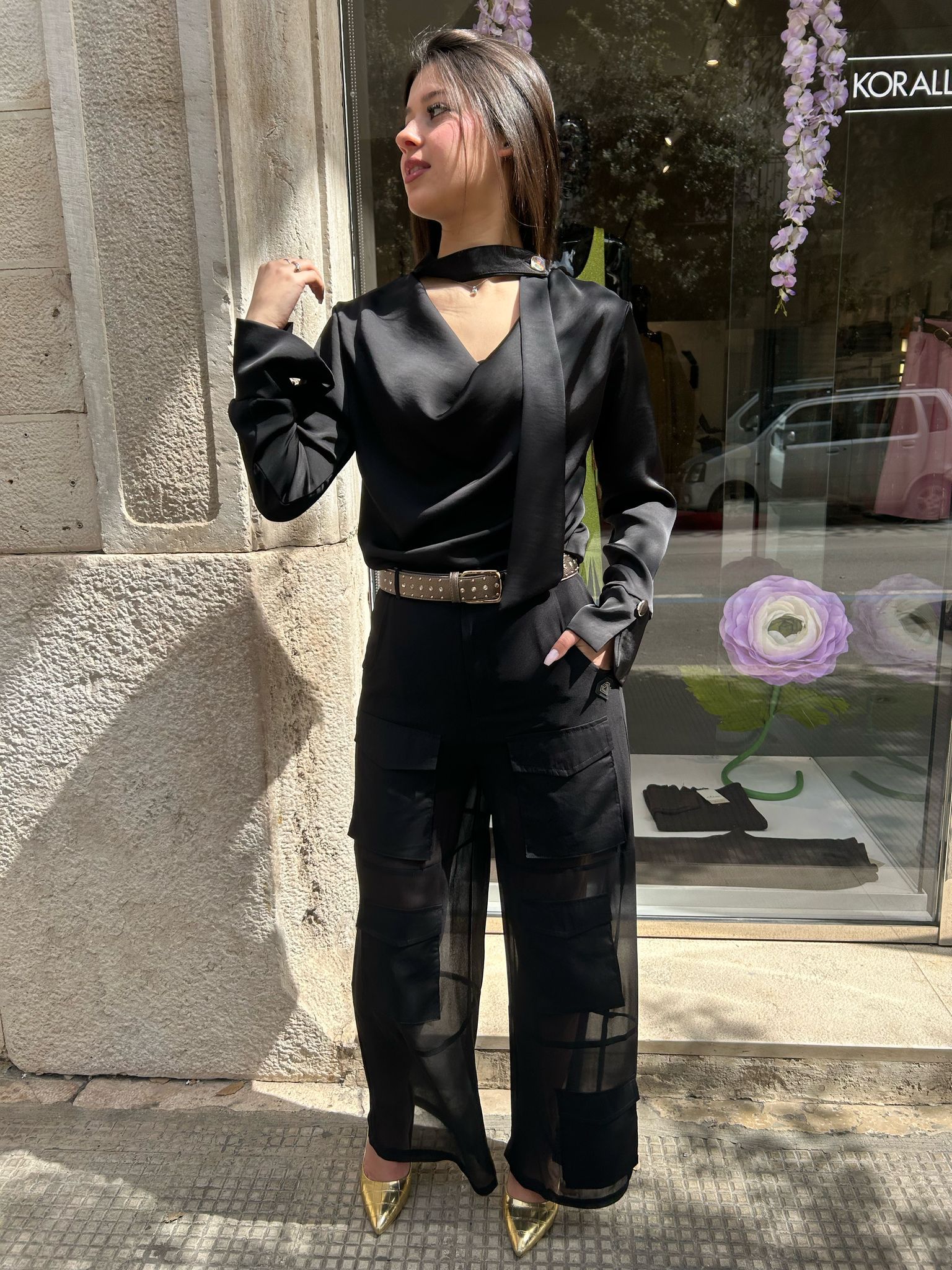 Una donna in tuta nera è in piedi davanti a un edificio.