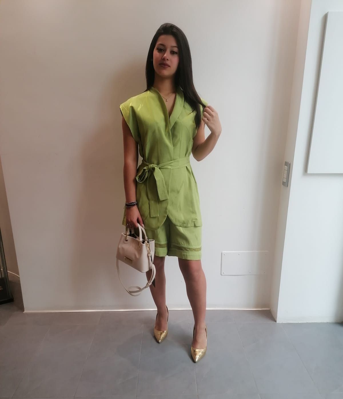 Una donna con un vestito verde tiene in mano una piccola borsa