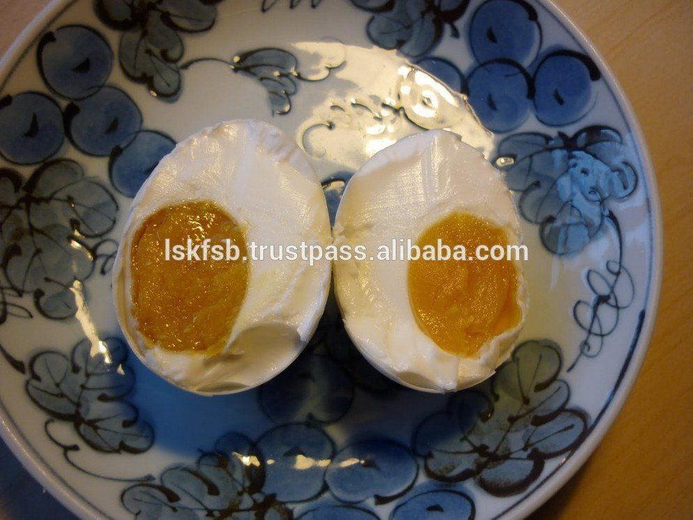 Halved salted duck egg, showing bright orange yolk and white albumen, on a blue and white patterned plate.