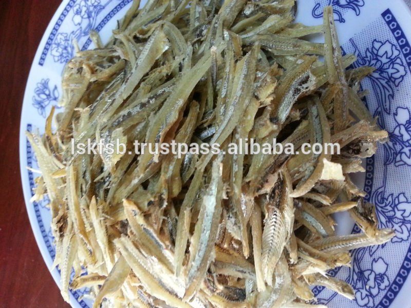Dried anchovies on a blue and white patterned plate, close up.