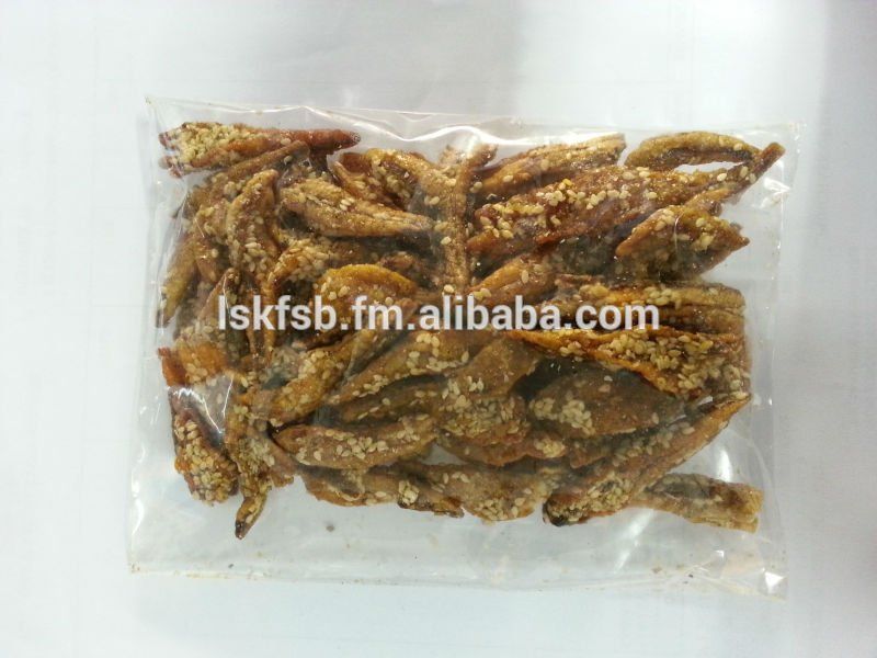 Bag of fried fish snacks coated in sesame seeds, on a white surface.