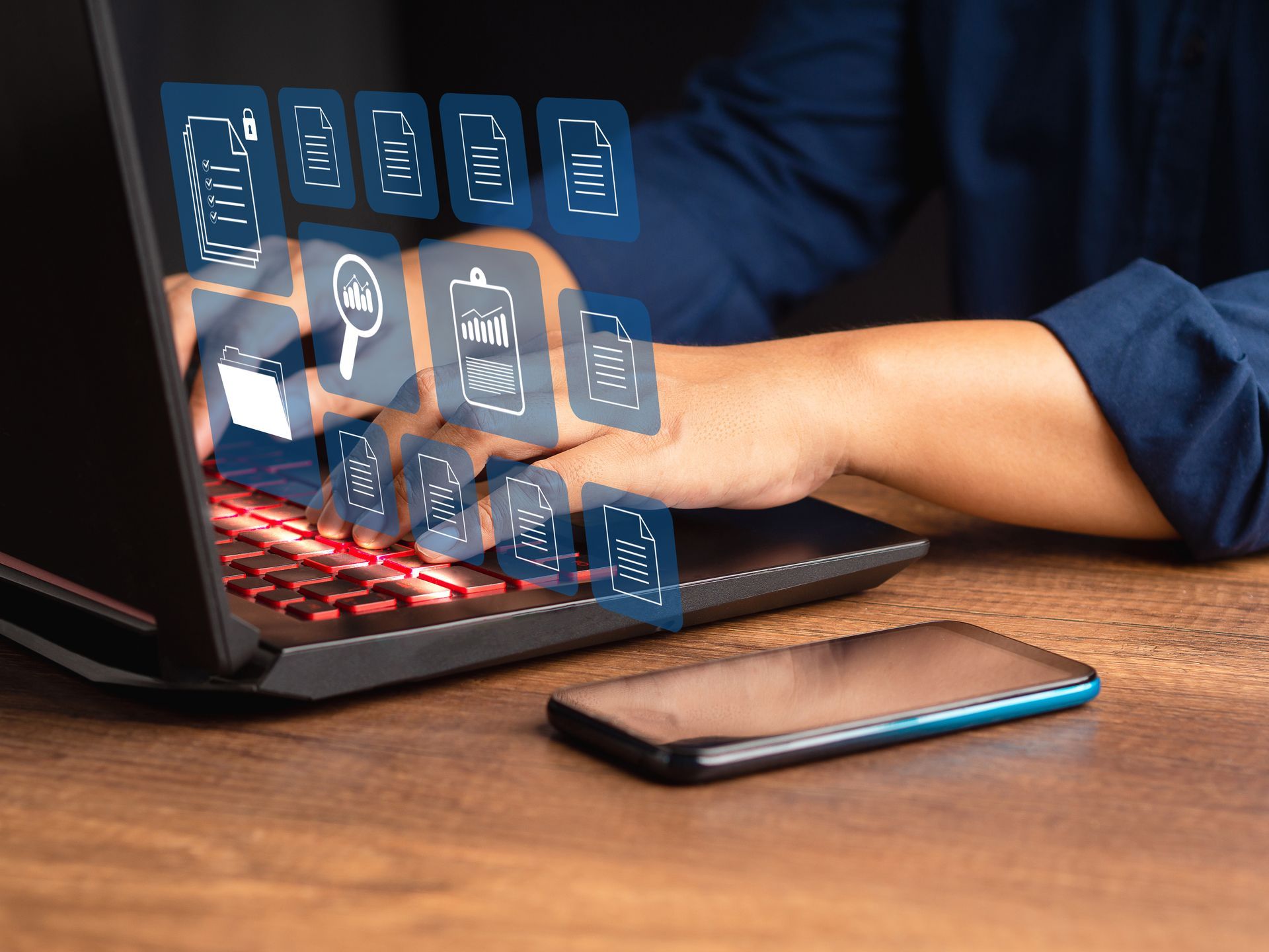 A person typing on a laptop with holographic business and file icons floating above the keyboard. A person typing on a laptop with holographic business and file icons floating above the keyboard.