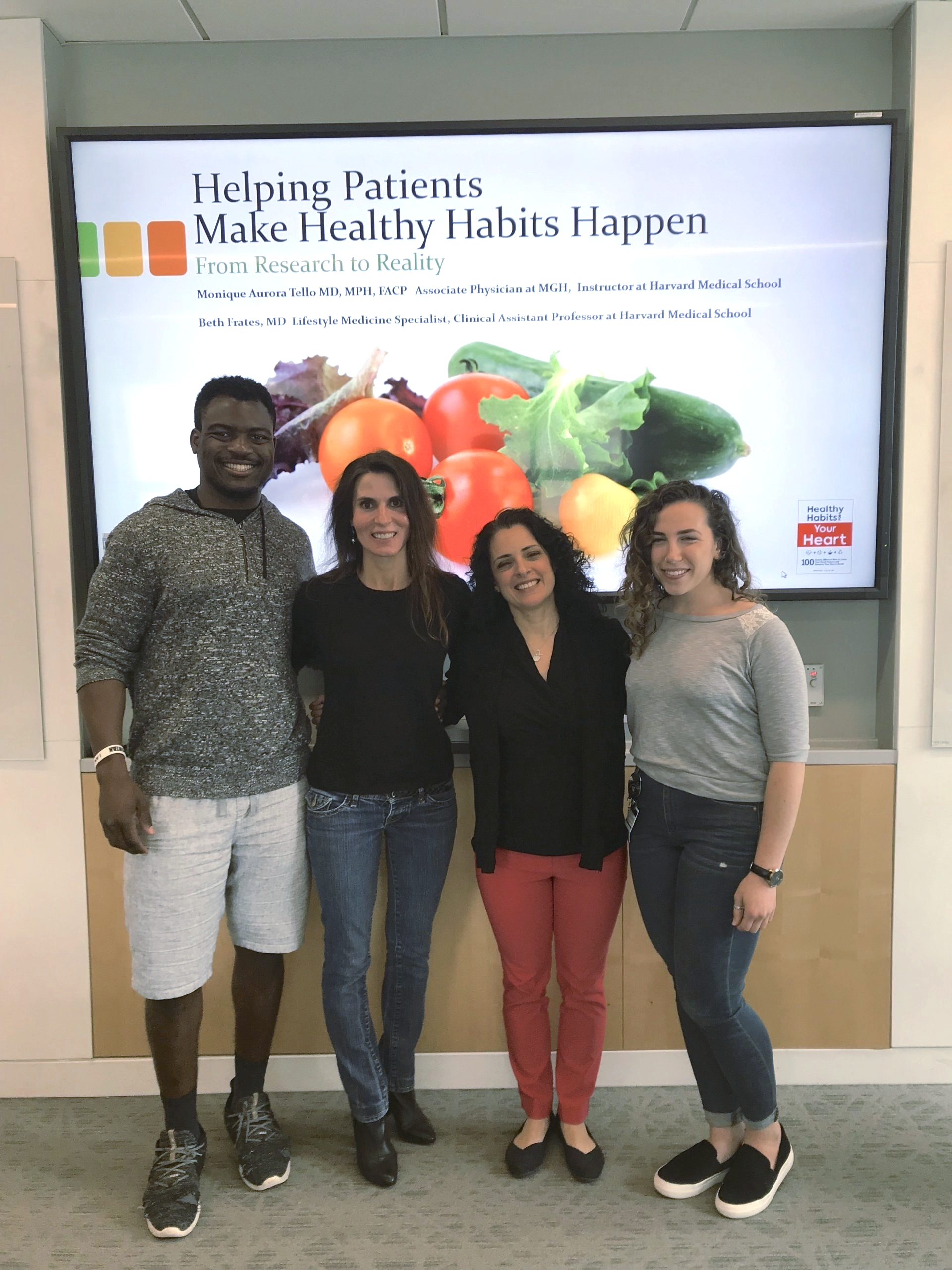 Beth Frates MD posing for a group photo with Harvard Medical School students next to a presentation.