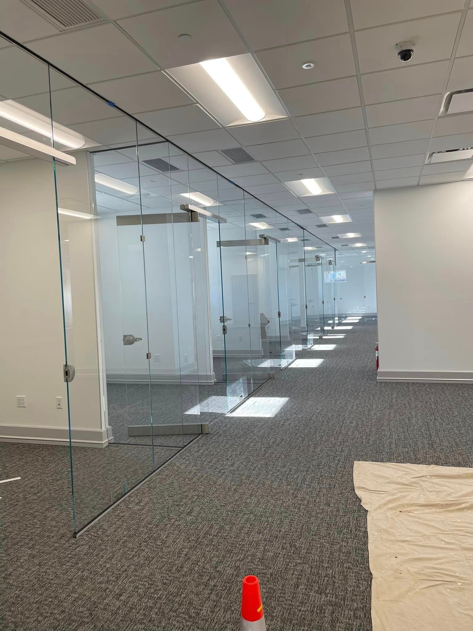 A long hallway in an office building with a lot of glass walls.