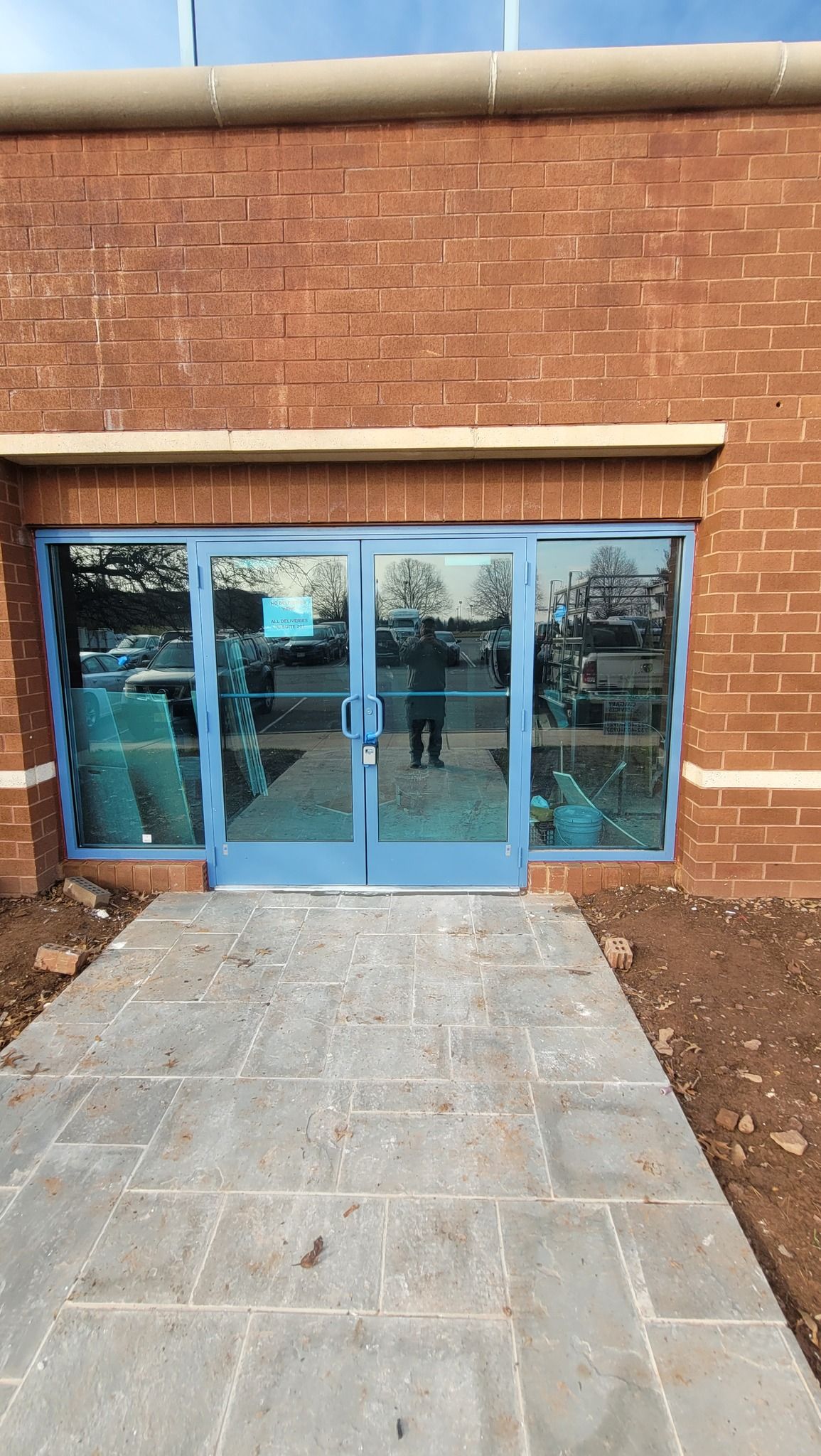 A brick building with a blue door and a walkway leading to it.