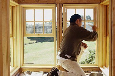 A man is installing a window in a house under construction