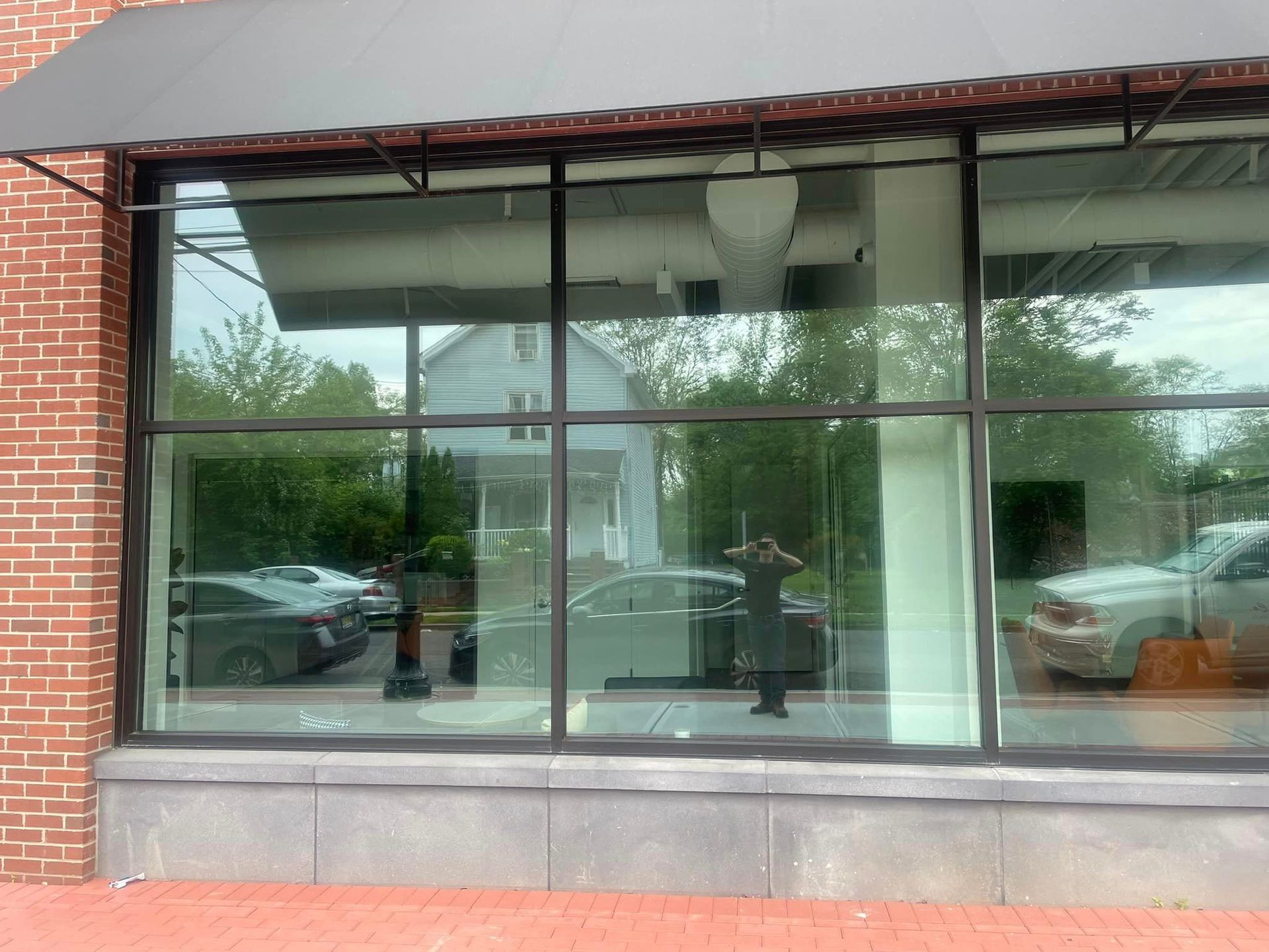 A brick building with a large window with a black awning