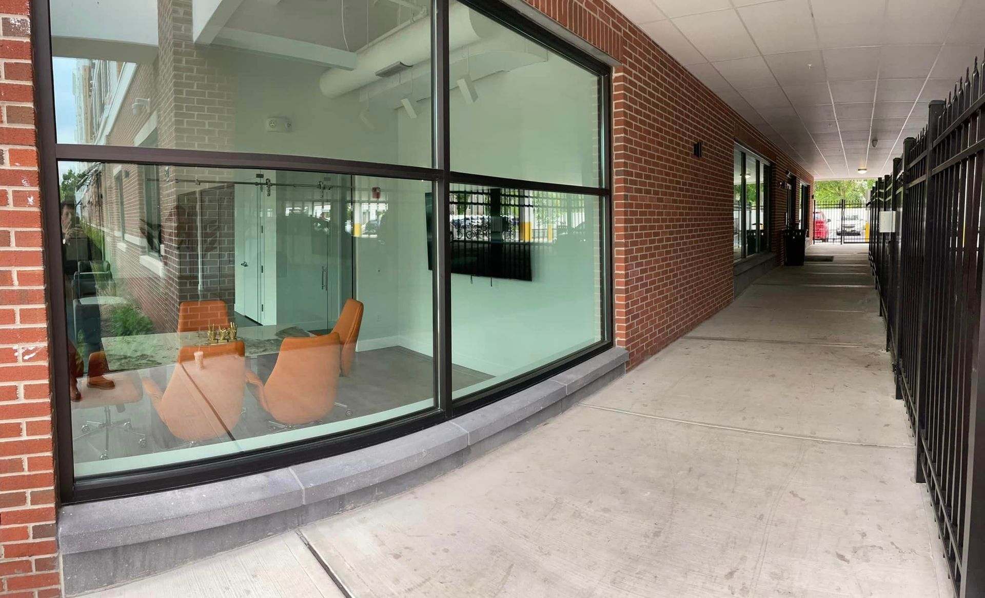 A hallway with a brick wall and a large window with chairs in front of it.