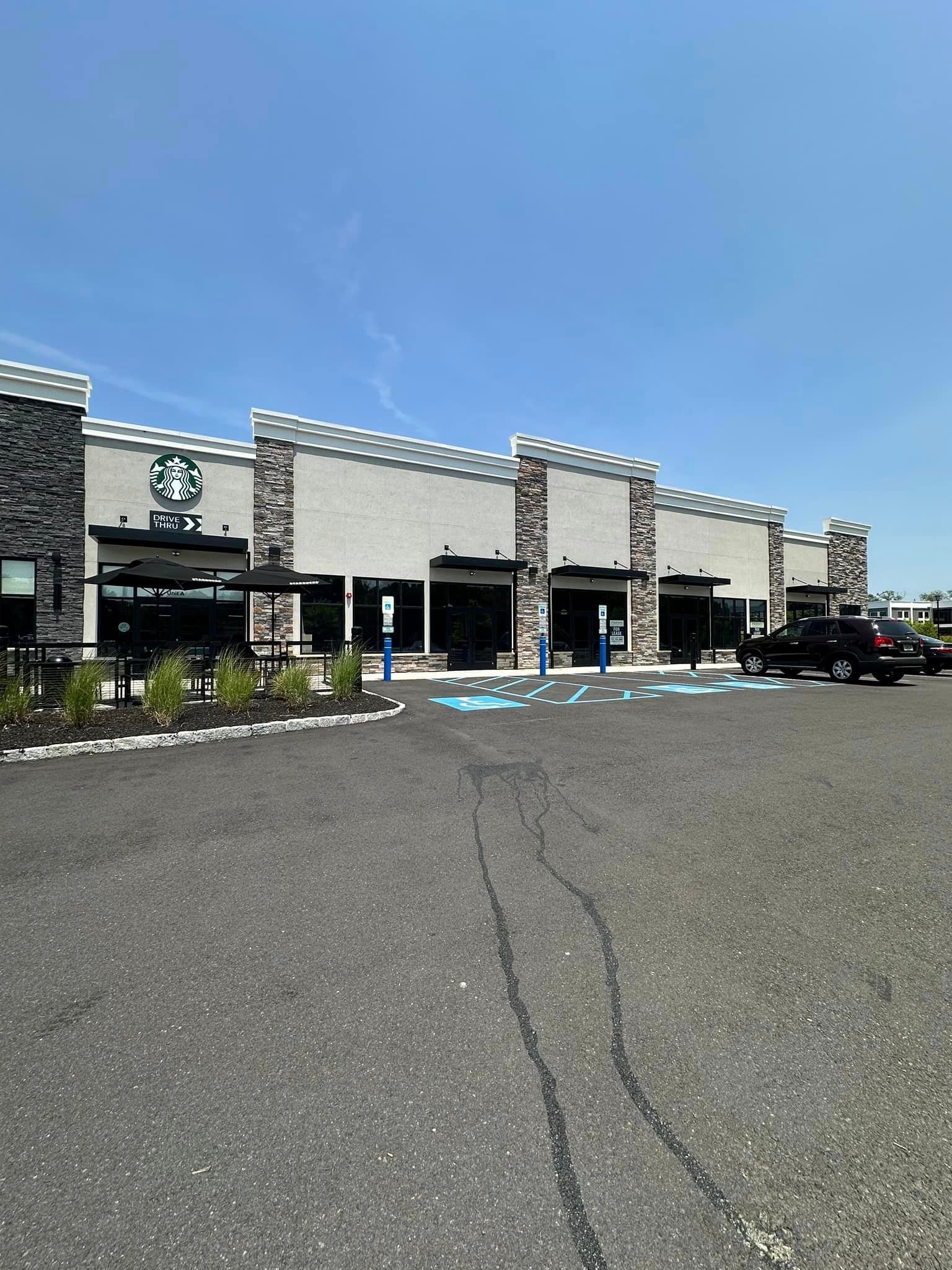 A starbucks coffee shop with cars parked in front of it on a sunny day.