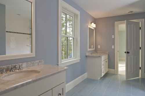 A bathroom with two sinks , two mirrors , and a window.