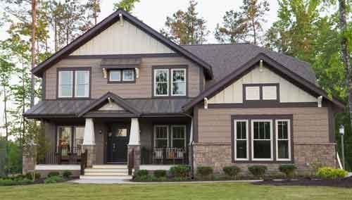 A large house with a lot of windows is sitting on top of a lush green lawn.