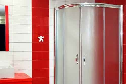 A bathroom with red and white tiles and a shower stall.