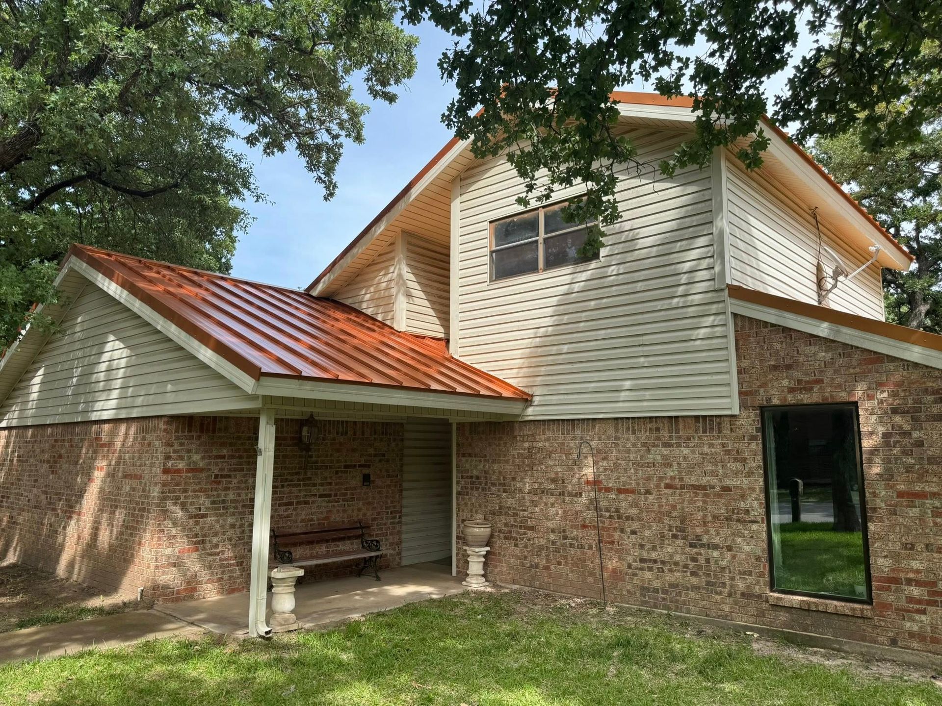 A brick house with a white siding and an orange roof