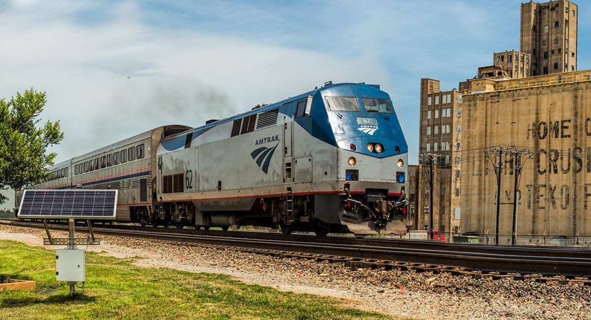 A train is going down the tracks next to a building.