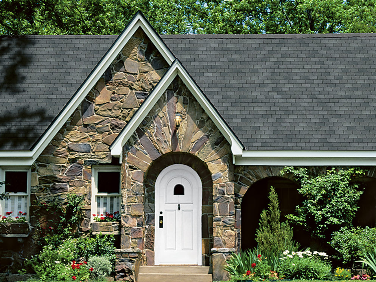 A stone house with a white door and a black roof
