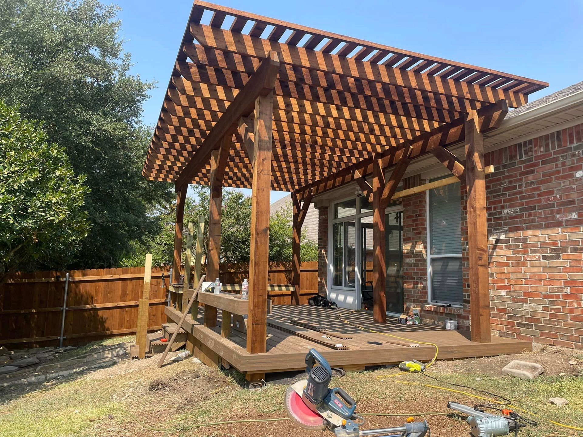 A wooden pergola is being built over a deck in a backyard.