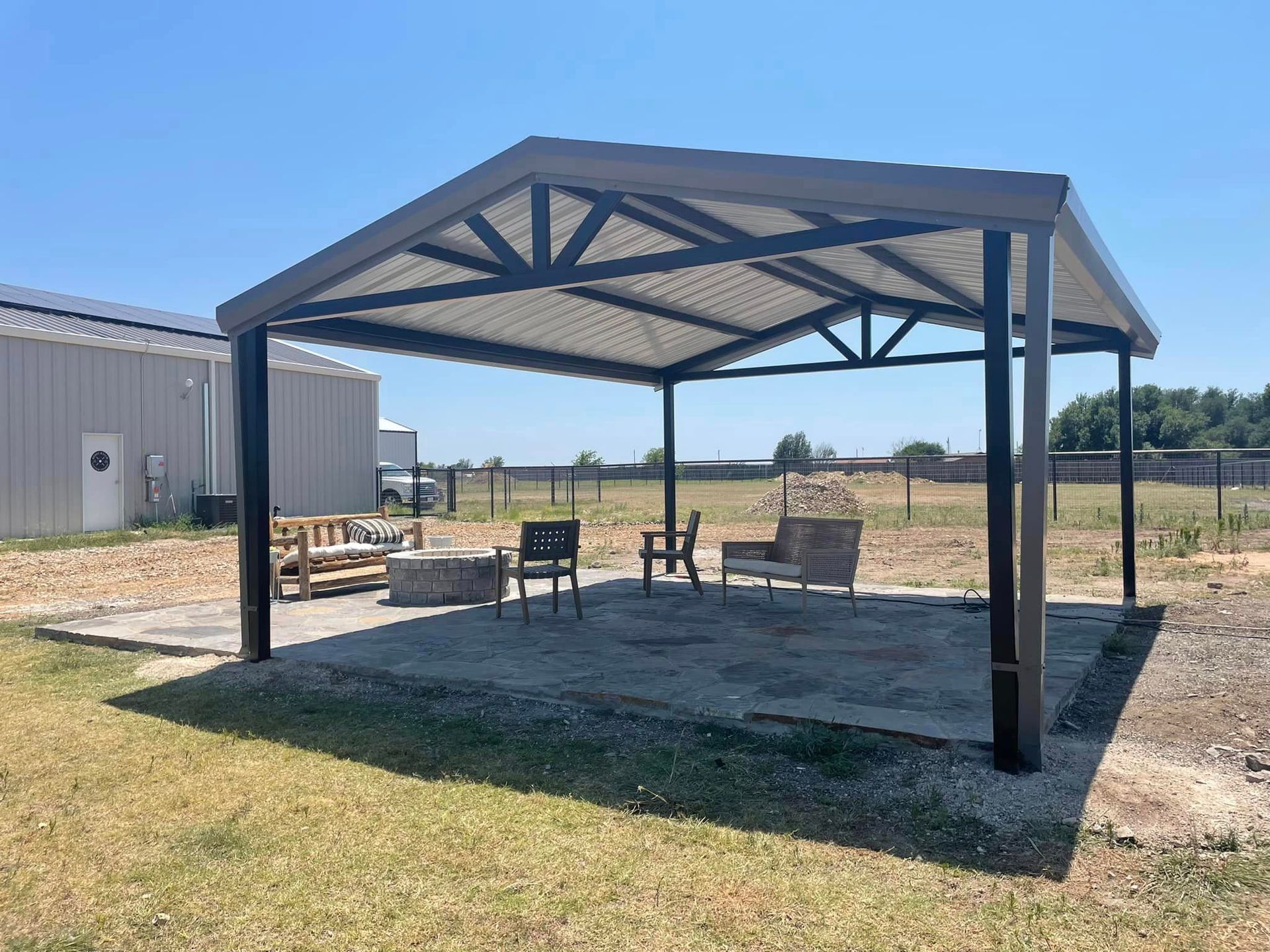 A covered area with chairs and a table under a canopy in a field.