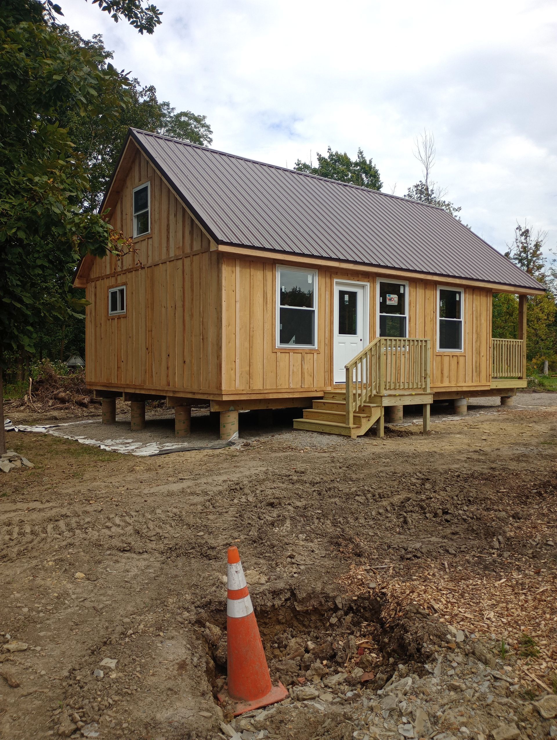 A small wooden house with a metal roof and stairs