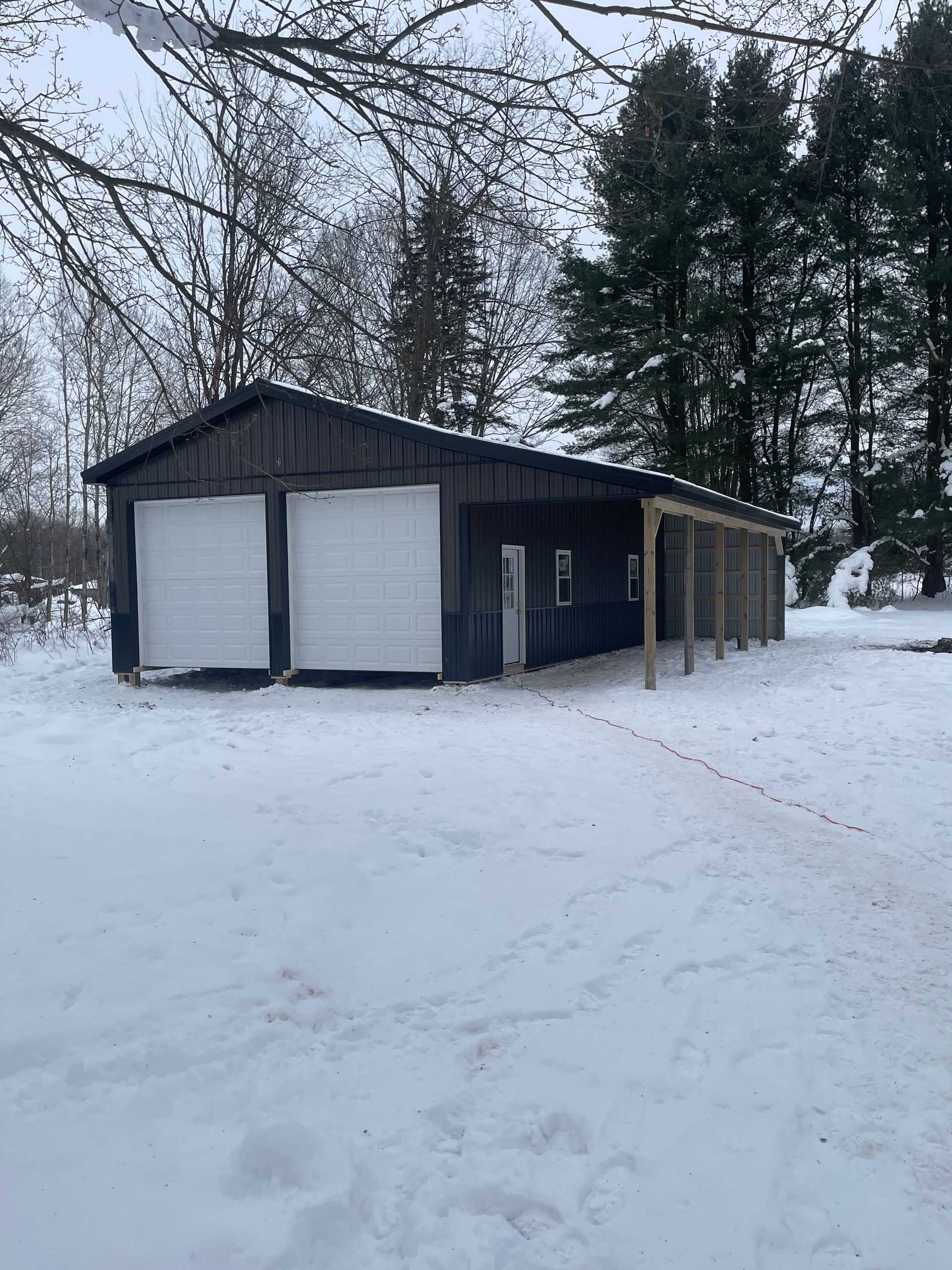 A garage with two garage doors is covered in snow.
