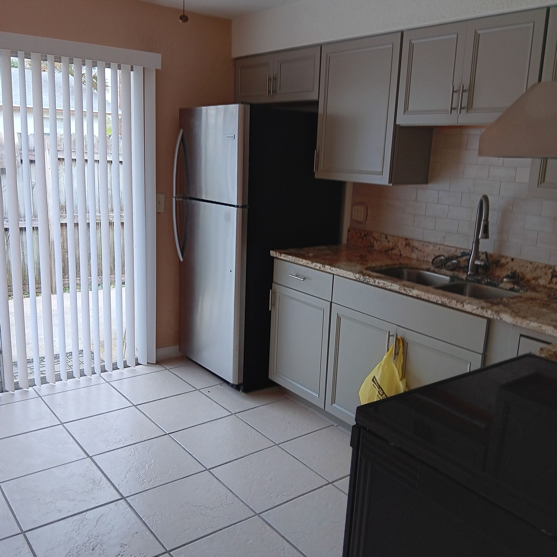 Kitchen with gray cabinets, stainless steel refrigerator, and sliding glass door.