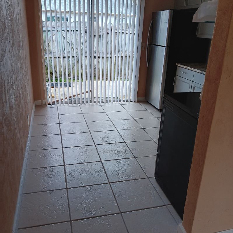 Kitchen with tile floor, stainless steel refrigerator, and sliding glass door to a patio.