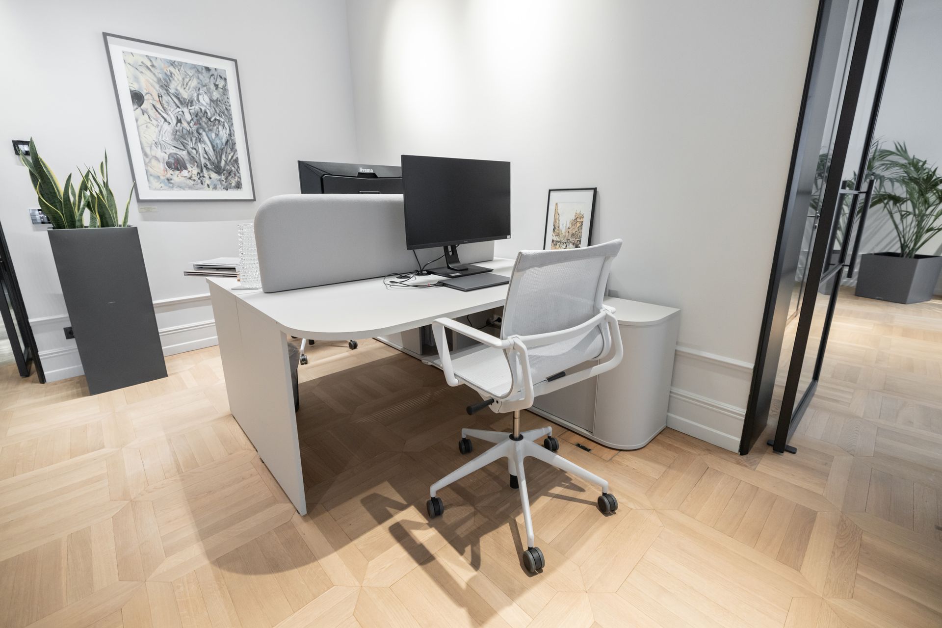 Moderner Bürotisch mit Computer, Stuhl und Zierpflanzen.