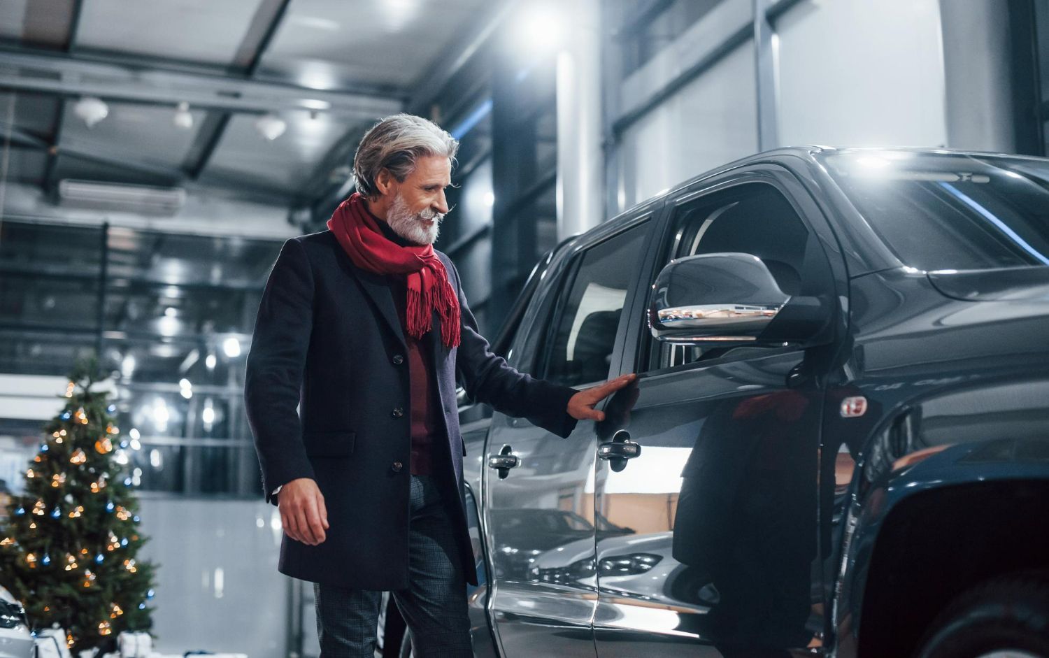 A man is standing next to a car in a showroom.