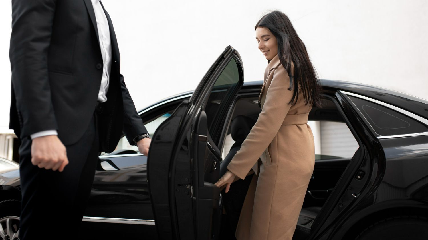 A man in a suit is helping a woman get out of a car.