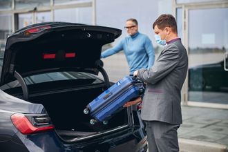 chauffeur putting luggage in boot