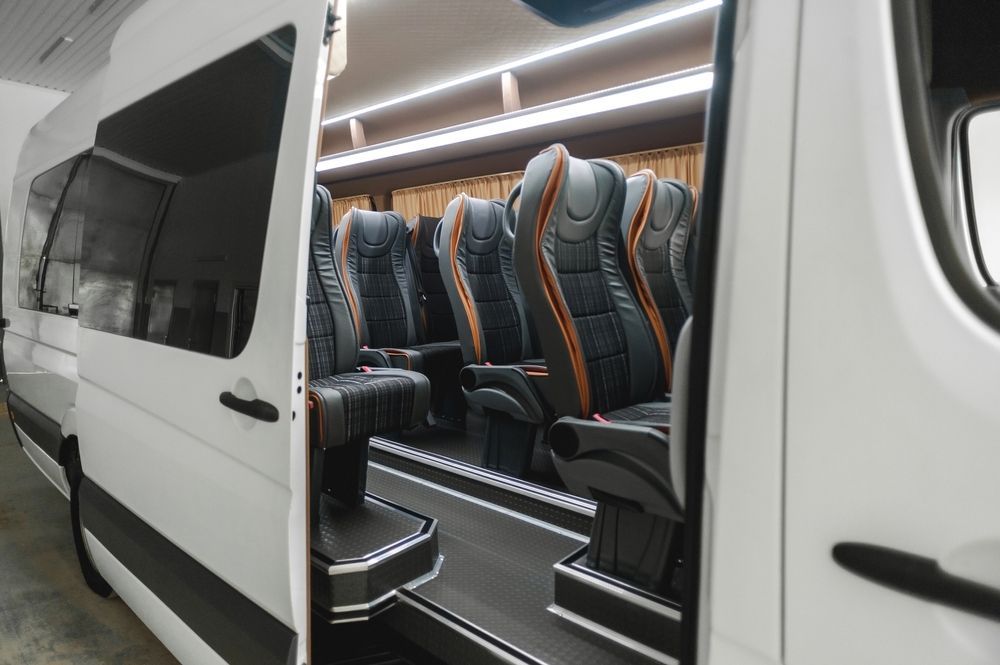 The inside of a white van with the door open and seats.