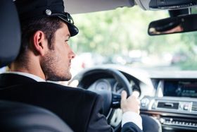 a man in a suit and hat is driving a car