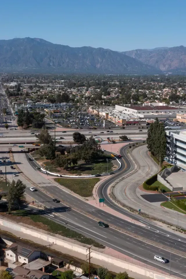 El monte fence company - Aerial view of a cityscape with winding roads, buildings, and mountains in the background under a clear blue sky.